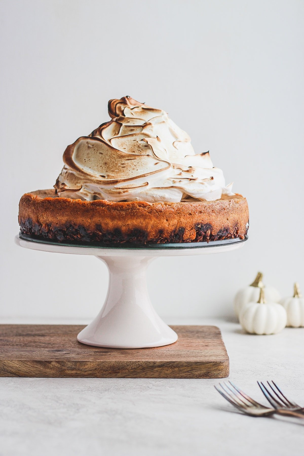 A vegan pumpkin cheesecake on a cake stand.