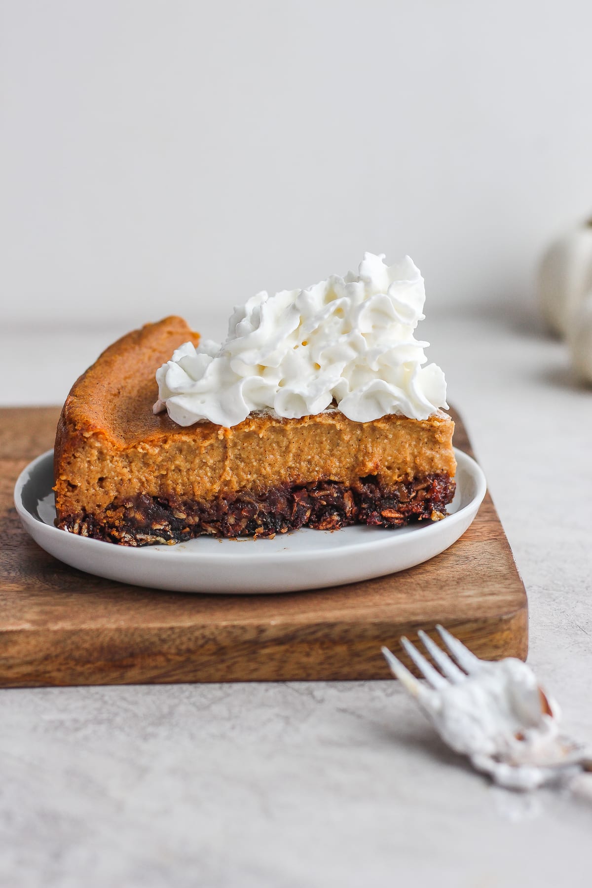 A piece of vegan pumpkin cheesecake on a white plate with a fork.