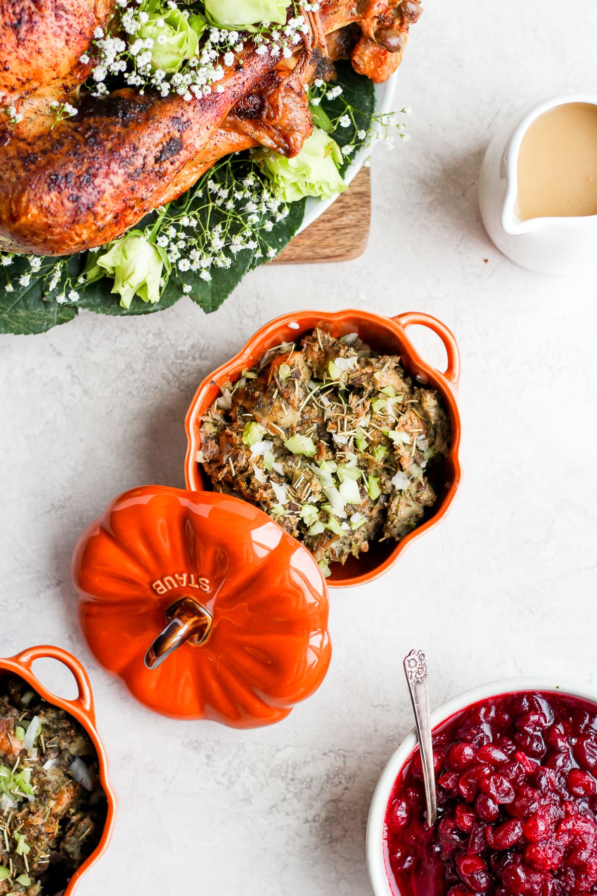 A small orange dish of giblet stuffing surrounded by other classic thanksgiving recipes.