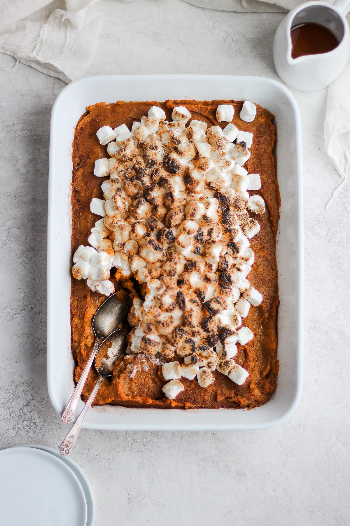 Sweet potato casserole in a white baking dish with two spoons.