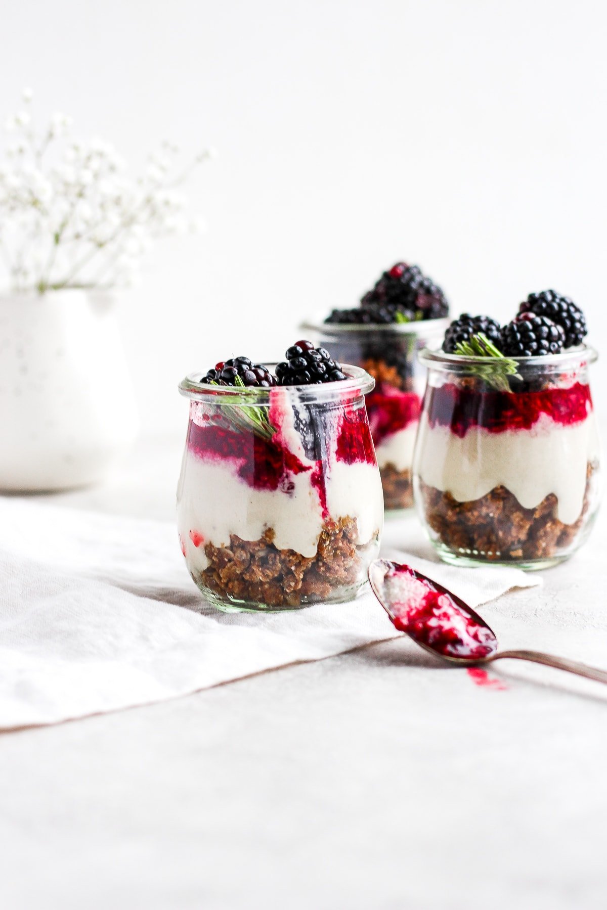 Three jars of blackberry cheesecake after a spoon had gone into one of them.