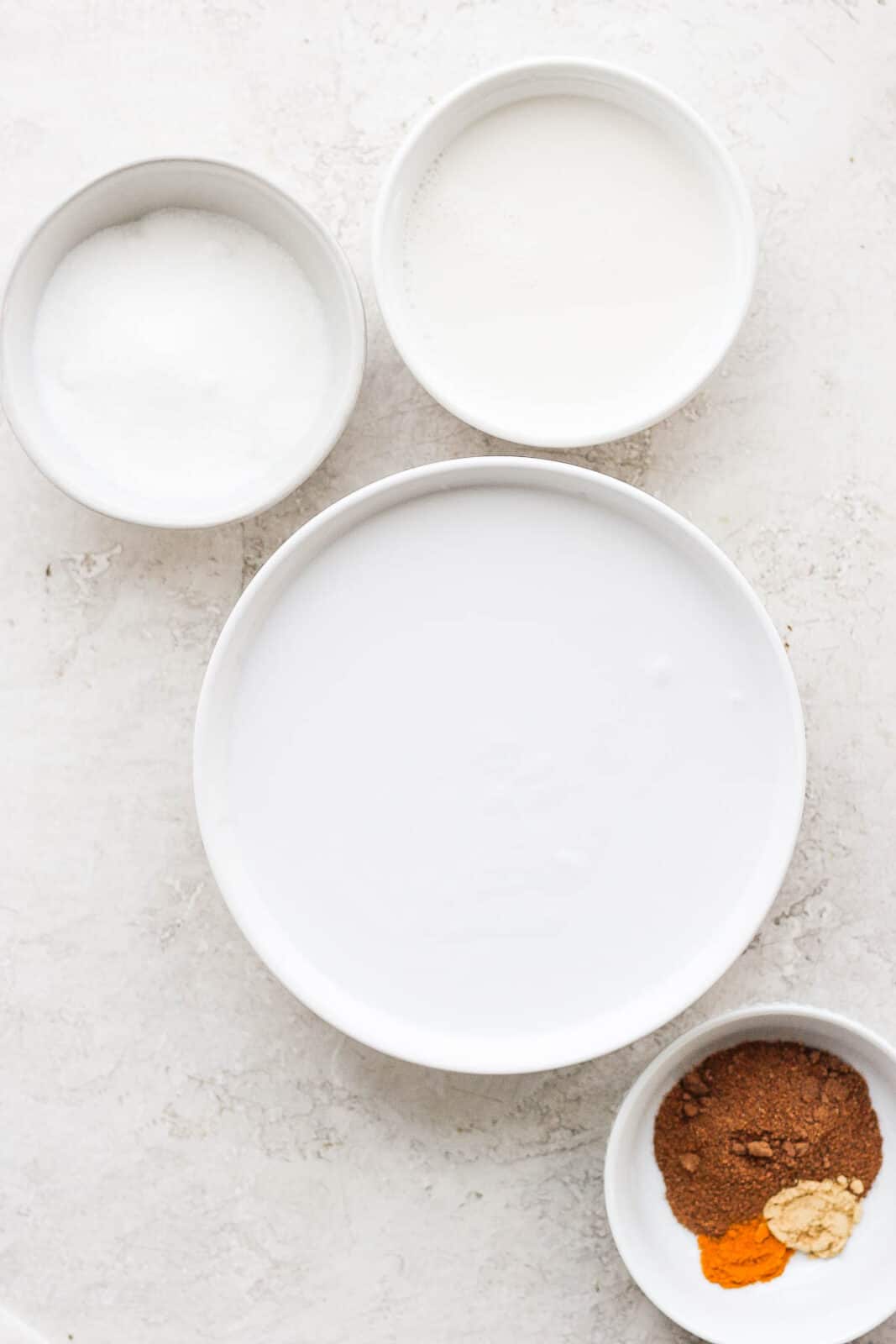 Ingredients for dairy free egg nog in separate bowls. 