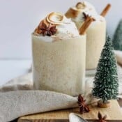 Two glasses of dairy-free egg nog garnished with cinnamon stick.