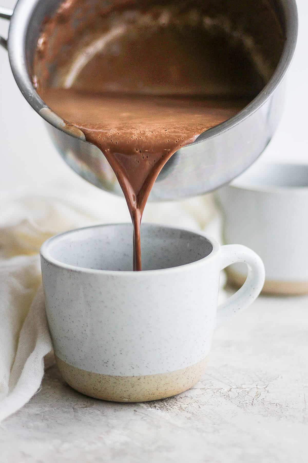 Someone pouring dairy free hot chocolate into mug.
