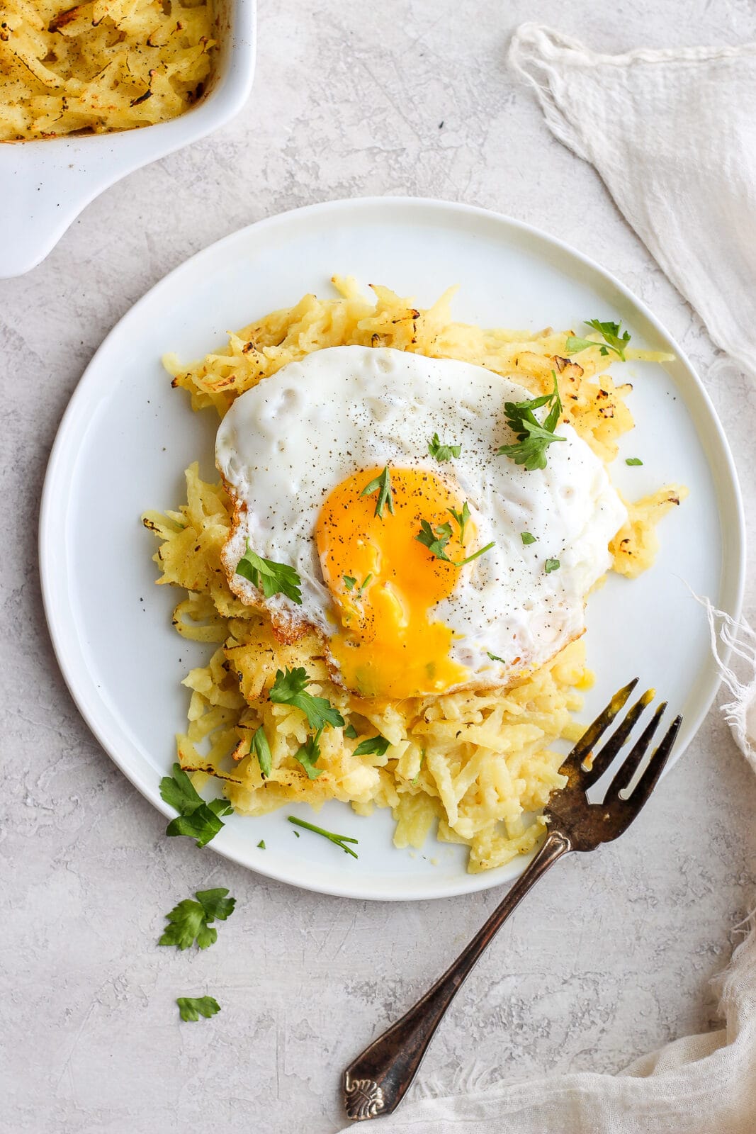 Dairy Free Cheesy Hashbrown Bake on a plate with an egg on top. 