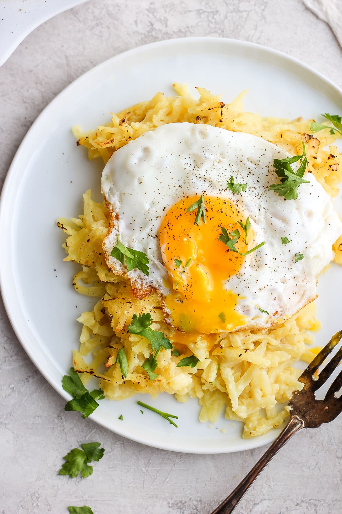 Dairy Free Cheesy Hashbrown Bake on a plate with an egg on top. 
