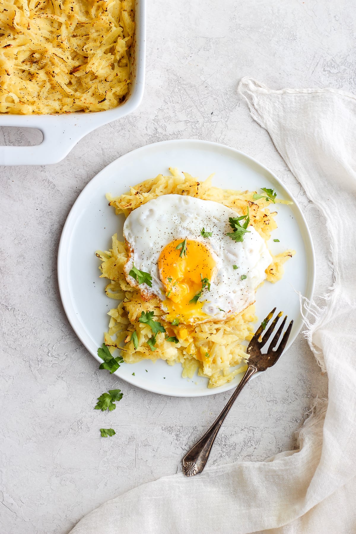 Dairy Free Cheesy Hashbrown Bake on a plate with an egg on top. 