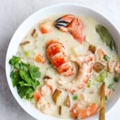 Dairy free chunky seafood chowder in a white bowl and a spoon sticking out the side.