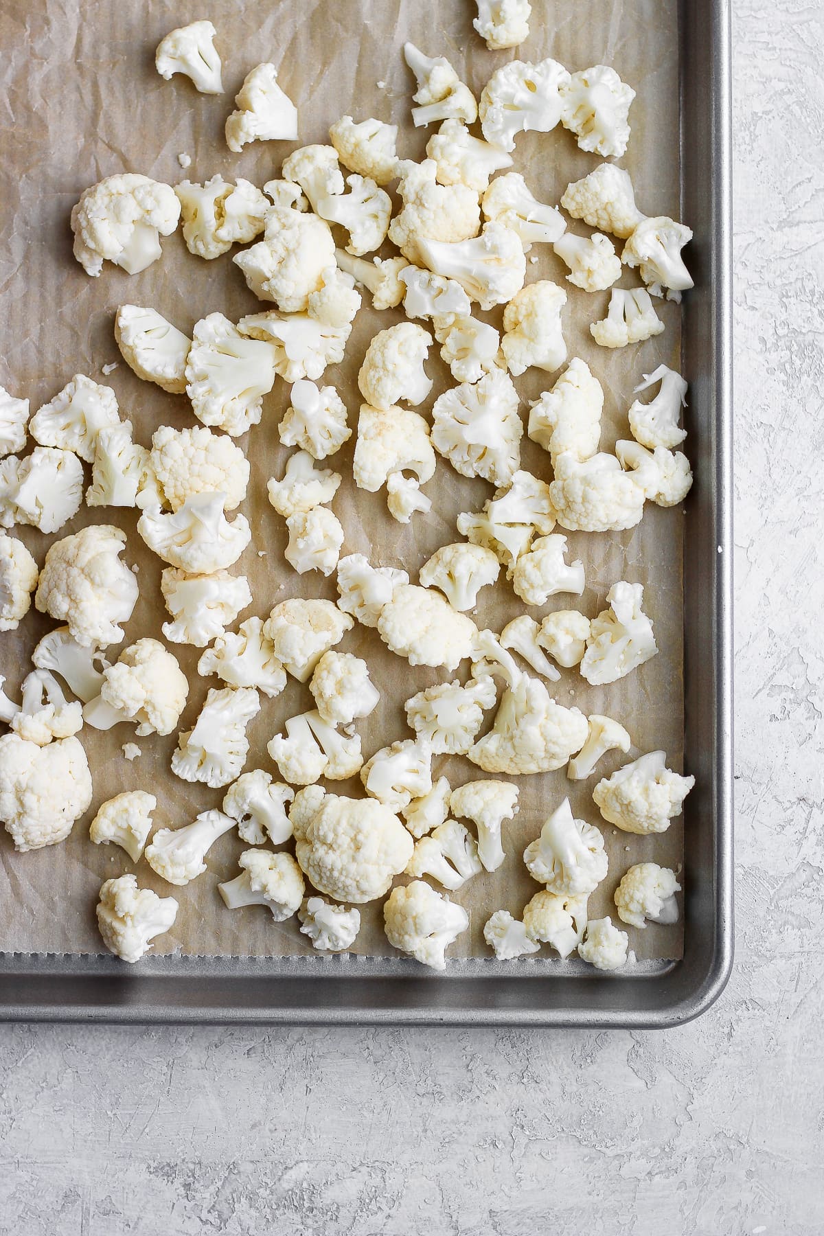 Cauliflower florets on a parchment-lined baking sheet.