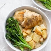 A bowl full of dairy free dijon chicken with broccolini next to another bowl of dijon chicken with broccolini.