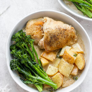 A bowl full of dairy free dijon chicken with broccolini next to another bowl of dijon chicken with broccolini.