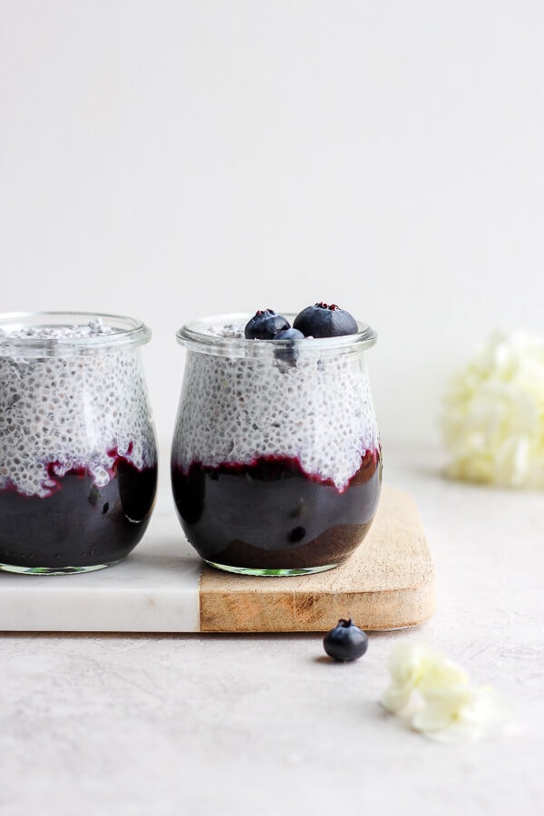 Two jars of coconut chia pudding on a marble and wood board.