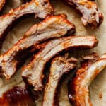Cut cooked ribs on a piece of parchment with bbq sauce on them and brush next to them.