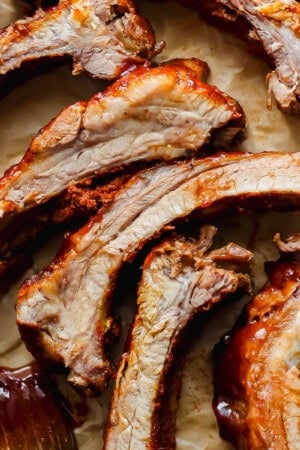 Cut cooked ribs on a piece of parchment with bbq sauce on them and brush next to them.