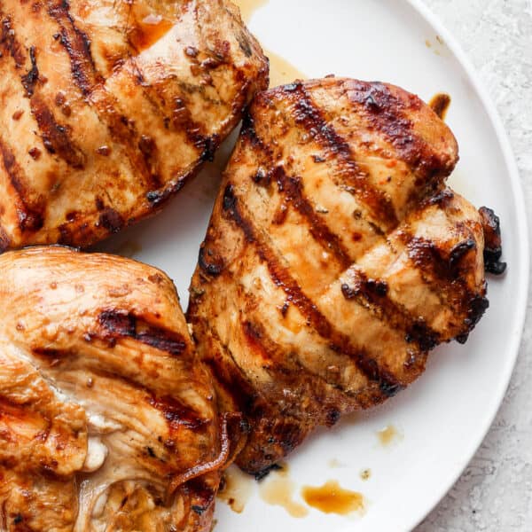 A plate of grilled chicken breasts with grill marks.