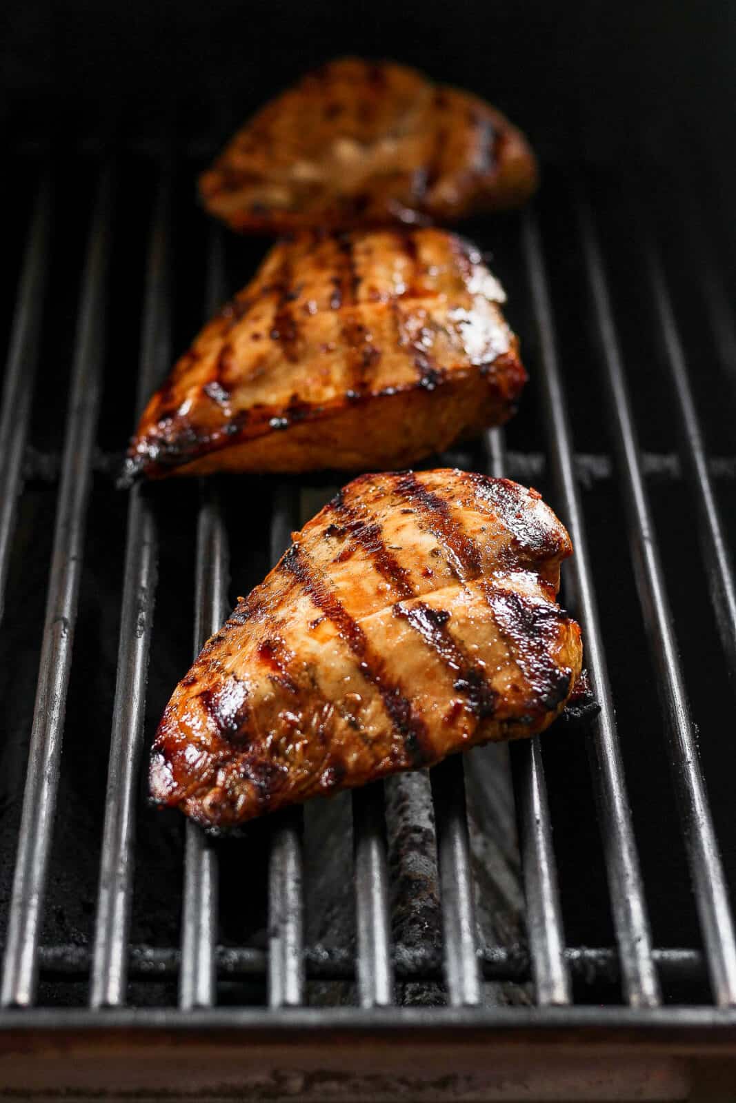 Three chicken breasts on the grill. 