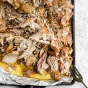 A foil-lined sheet pan full of shredded sous vide pork with a fork on the side.