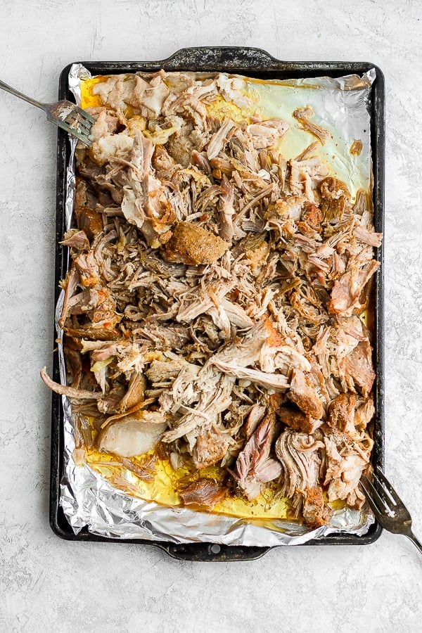 Foil-lined baking sheet with shredded sous vide pork shoulder on it. 