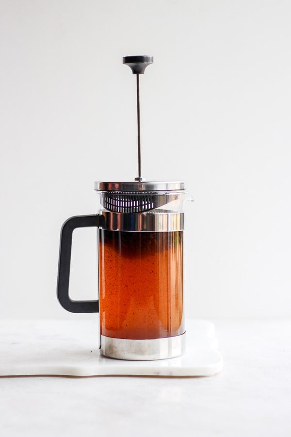 A glass French press showing the brown color of the water as it mixes with the ground coffee. 