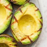 A grilled avocado on a plate with grill marks.