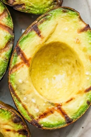 A grilled avocado on a plate with grill marks.