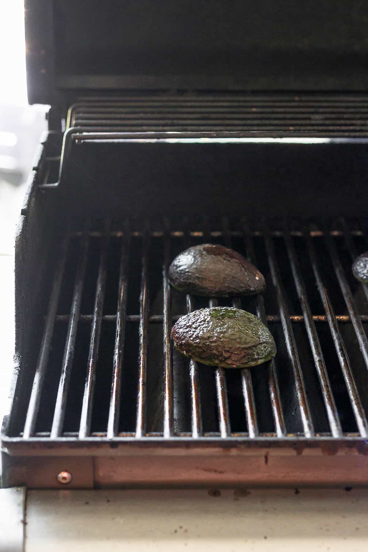 Avocado halves on a grill, cut side down.