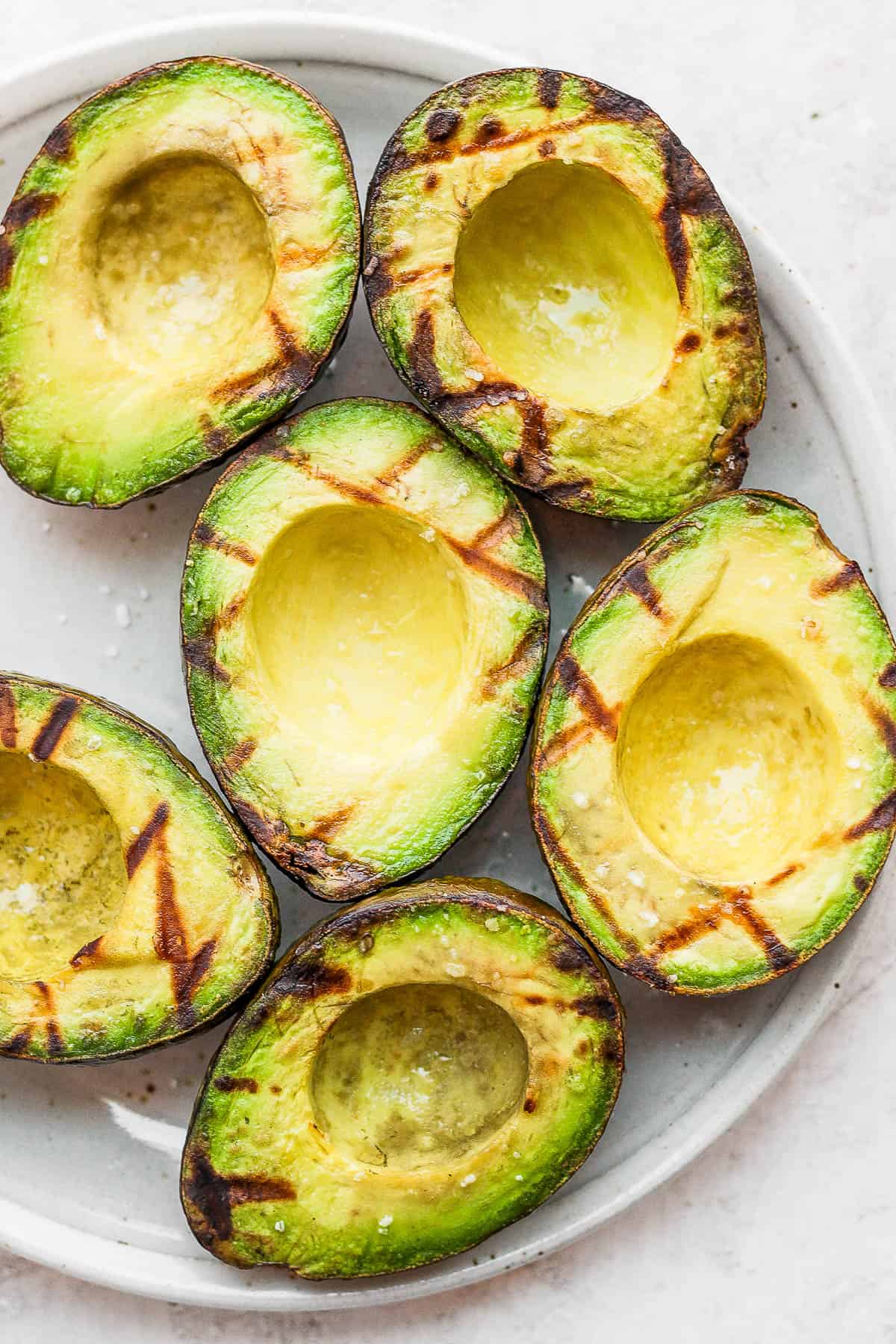 Plate of grilled avocados with grill marks.