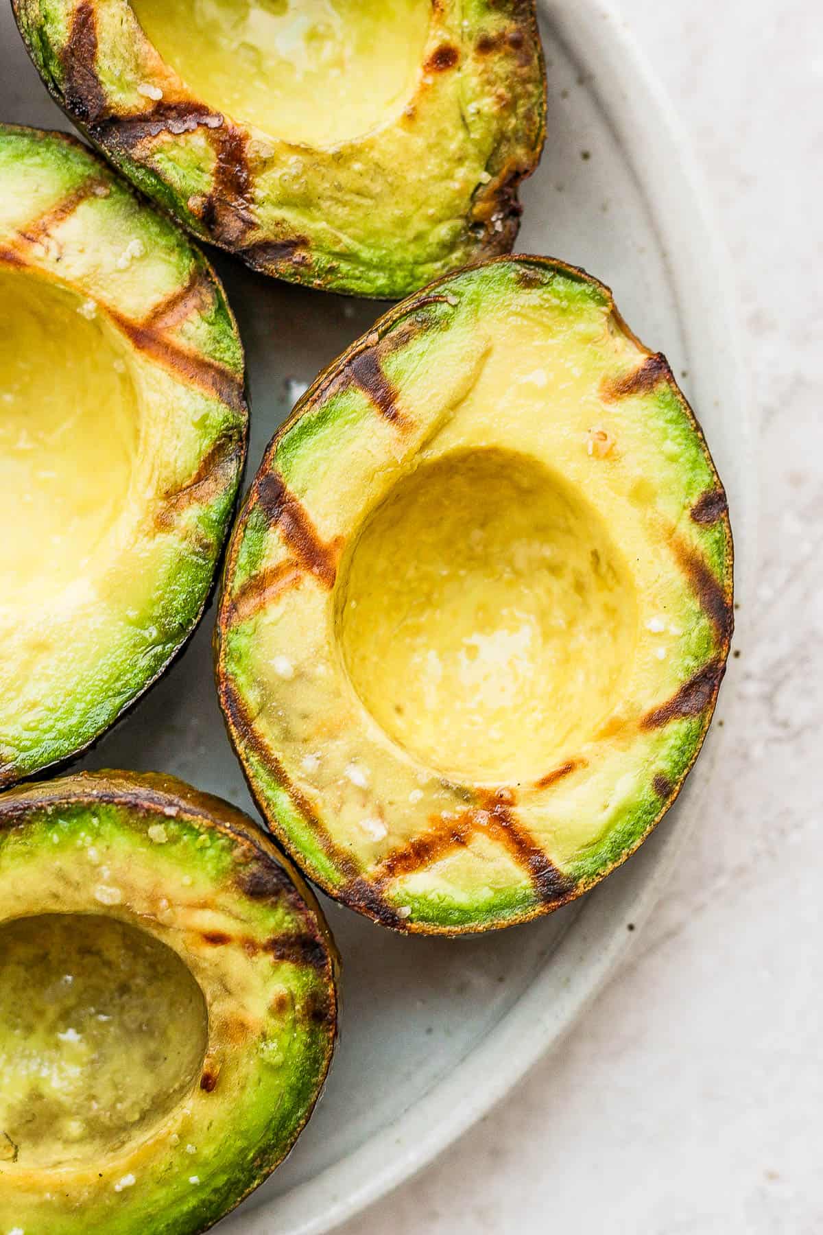 Grilled avocados with grill marks on a plate.