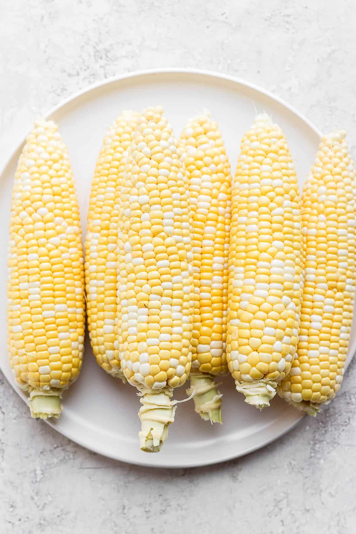 Six pieces of sweet corn on a plate. 