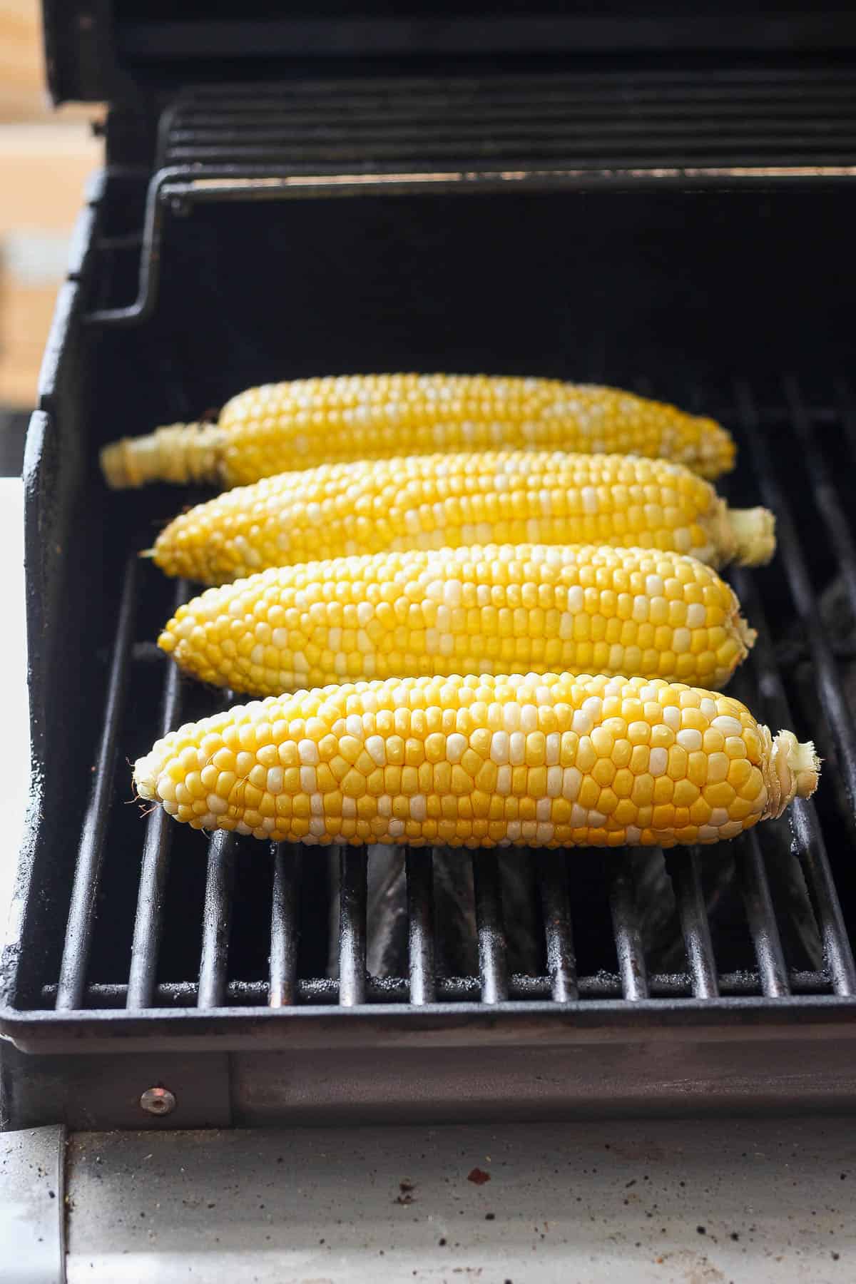 Four pieces of sweet corn on the grill. 