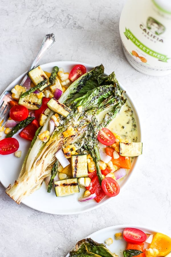 A grilled vegetable salad on a white plate with a fork.