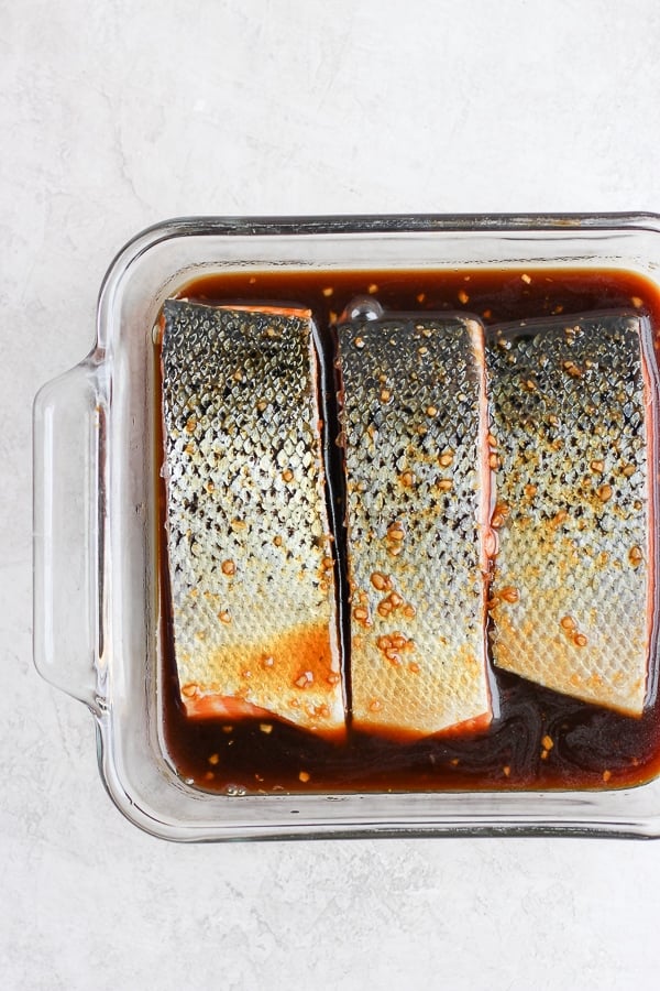 Salmon fillets marinating in a shallow glass dish.