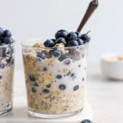 Blueberry overnight oats in glasses with a spoon in one glass.
