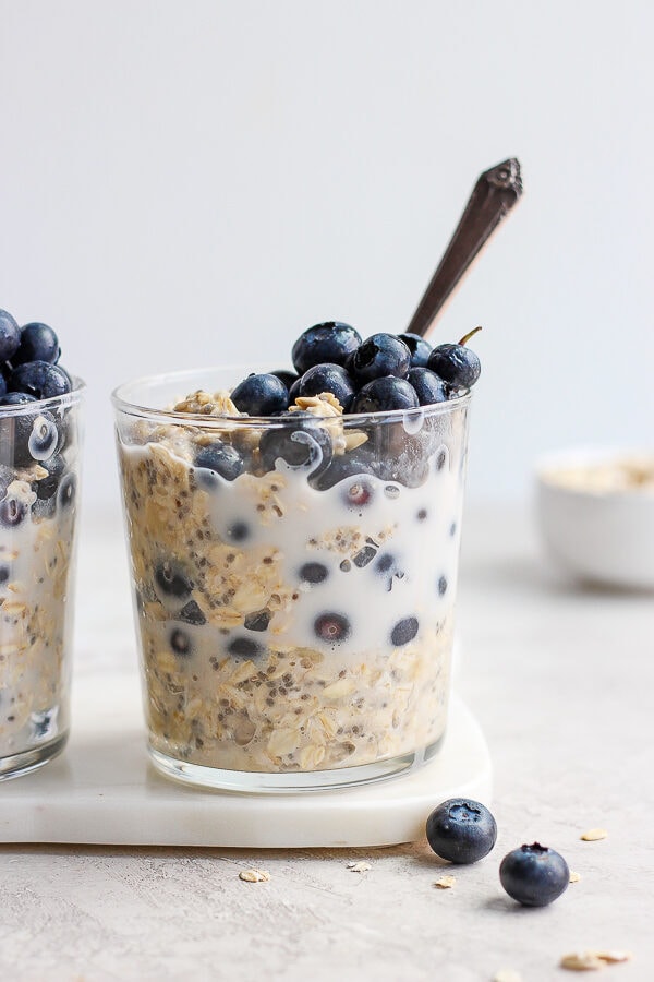 Blueberry overnight oats in glasses with a spoon in one glass.