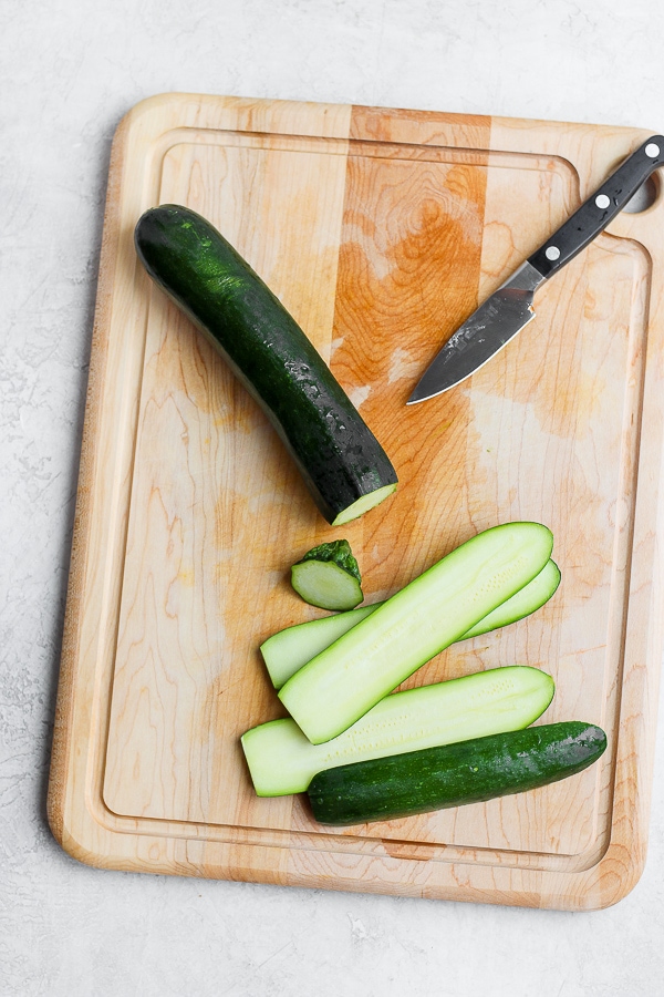 Zucchini on a cutting board with the ends cut off.