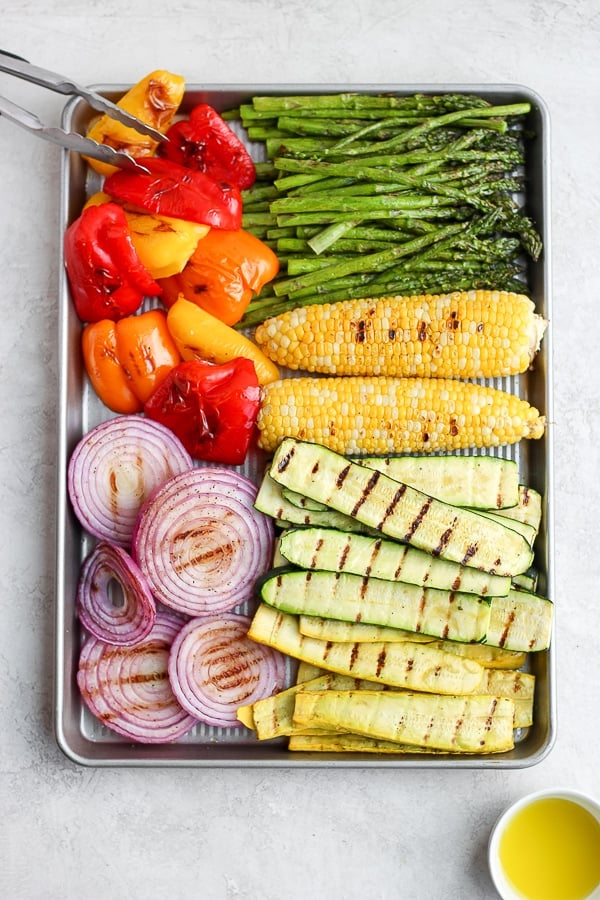 A large baking sheet filled with grilled veggies and sweet corn. 