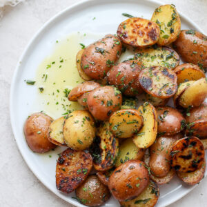 Halved herbed potatoes on a white plate.