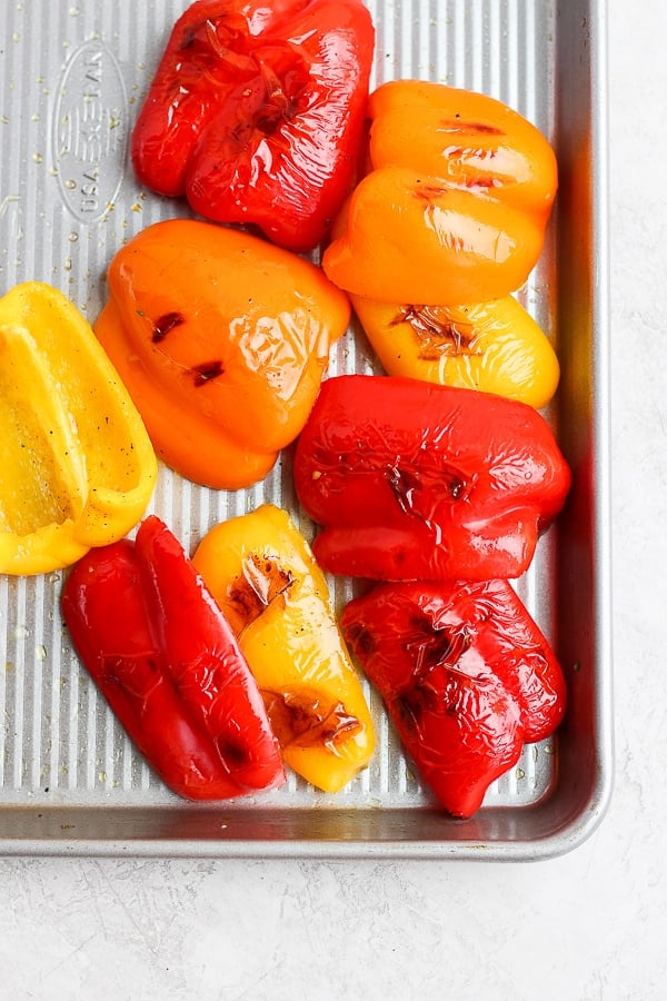 A baking dish with yellow and red grilled bell peppers on it. 