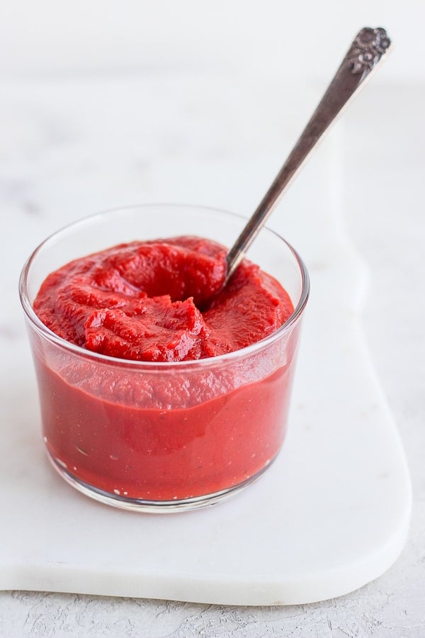 Homemade ketchup in a small glass with a spoon.