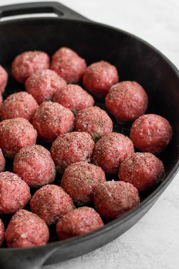 Meatballs browning in a cast iron skillet. 