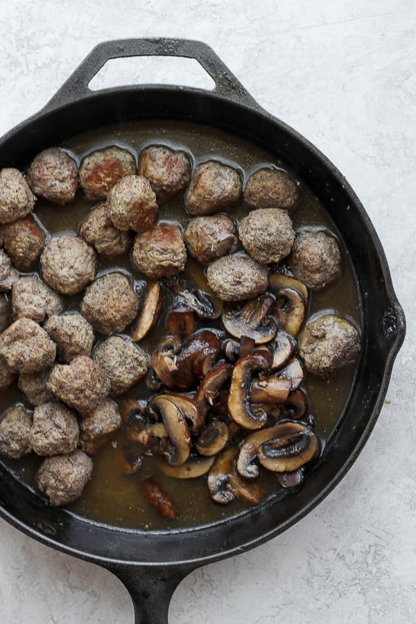 Cooked meatballs and mushrooms added back to the gravy in a skillet.