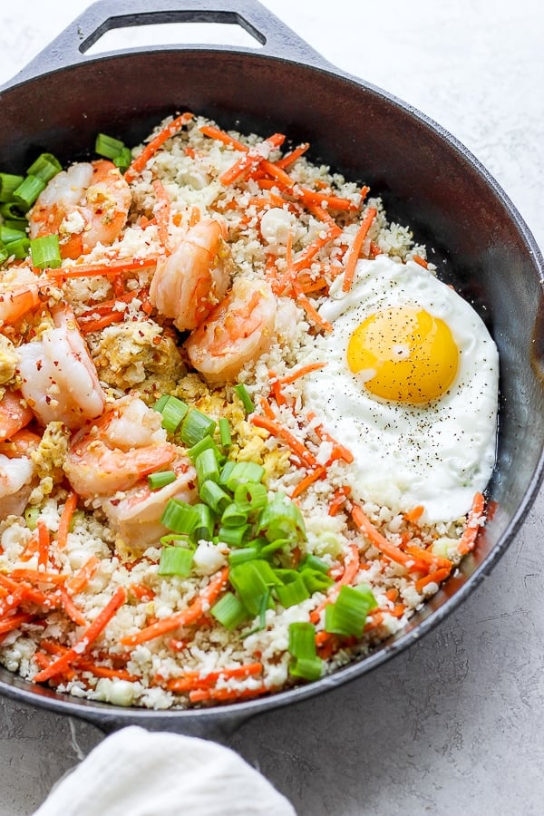 Shrimp fried cauliflower rice in a cast iron skillet with fried egg on top. 