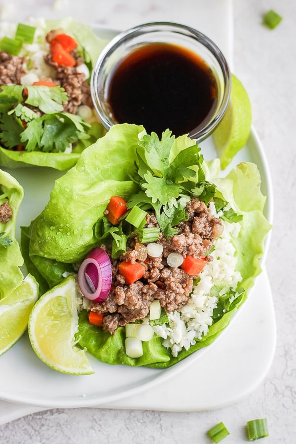 Lettuce wraps on a plate with a small dish of sauce.