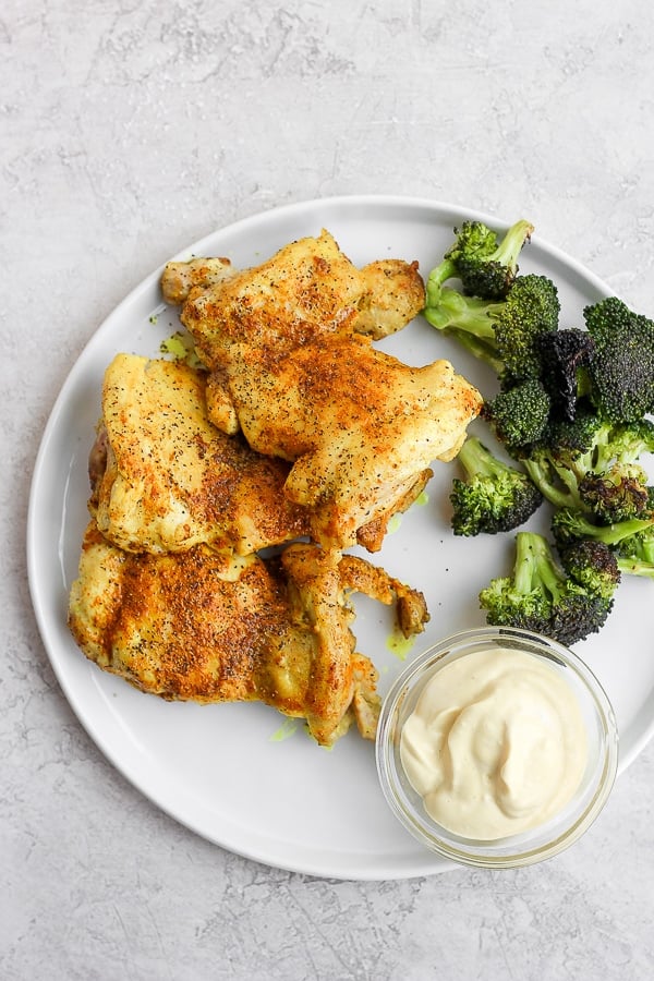 Stove top chicken thighs on a plate with broccoli and mustard mayo. 