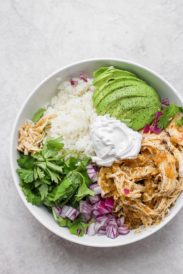 Salsa verde chicken in a bowl with rice, avocado and fresh cilantro. 