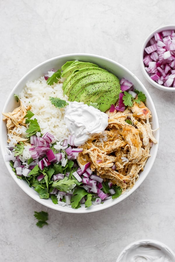salsa verde chicken in a bowl with rice, avocado and fresh cilantro. 