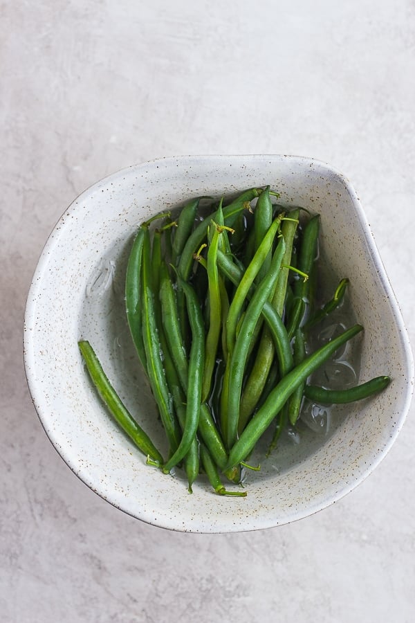 Steamed green beans in an ice bath.