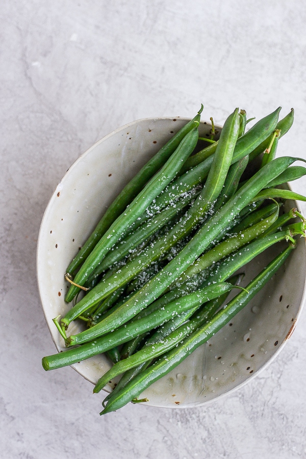 Steamed green beans in a bowl with salt.