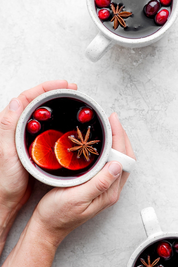 Two hands holding a mug of mulled wine.