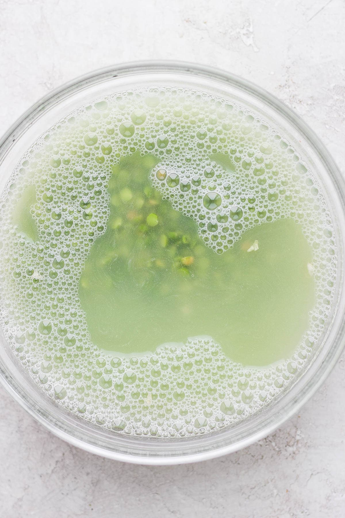 Green split peas soaking in water in a glass bowl. 